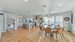 A modern kitchen with white cabinets, a central island, and pendant lighting. - Beach Access Private Pool, Ping-pong, Firepit, Swings, & Views Tipsea Turtle (Port Aransas)
