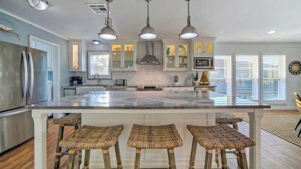 A modern kitchen with a central island, bar stools, stainless steel appliances, and pendant lighting. - Beach Access Private Pool, Ping-pong, Firepit, Swings, & Views Tipsea Turtle (Port Aransas)
