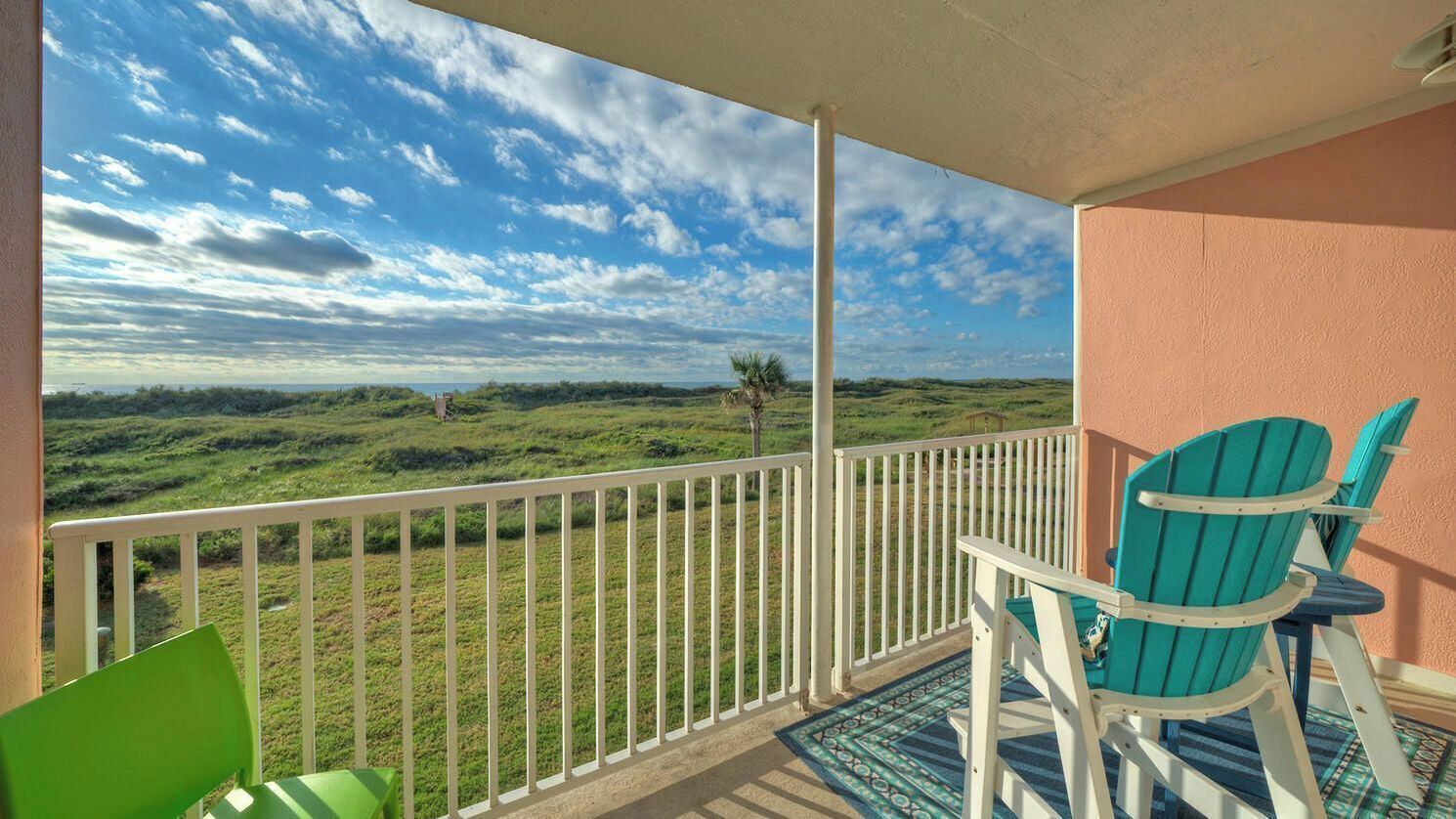 A balcony with a view of a grassy landscape and a clear sky.