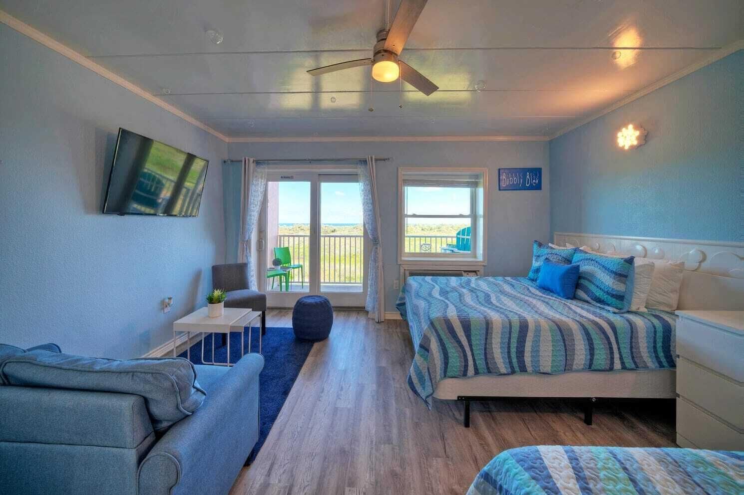 Een slaapkamer met een bed, een stoel, een tafeltje en een balkon met uitzicht.