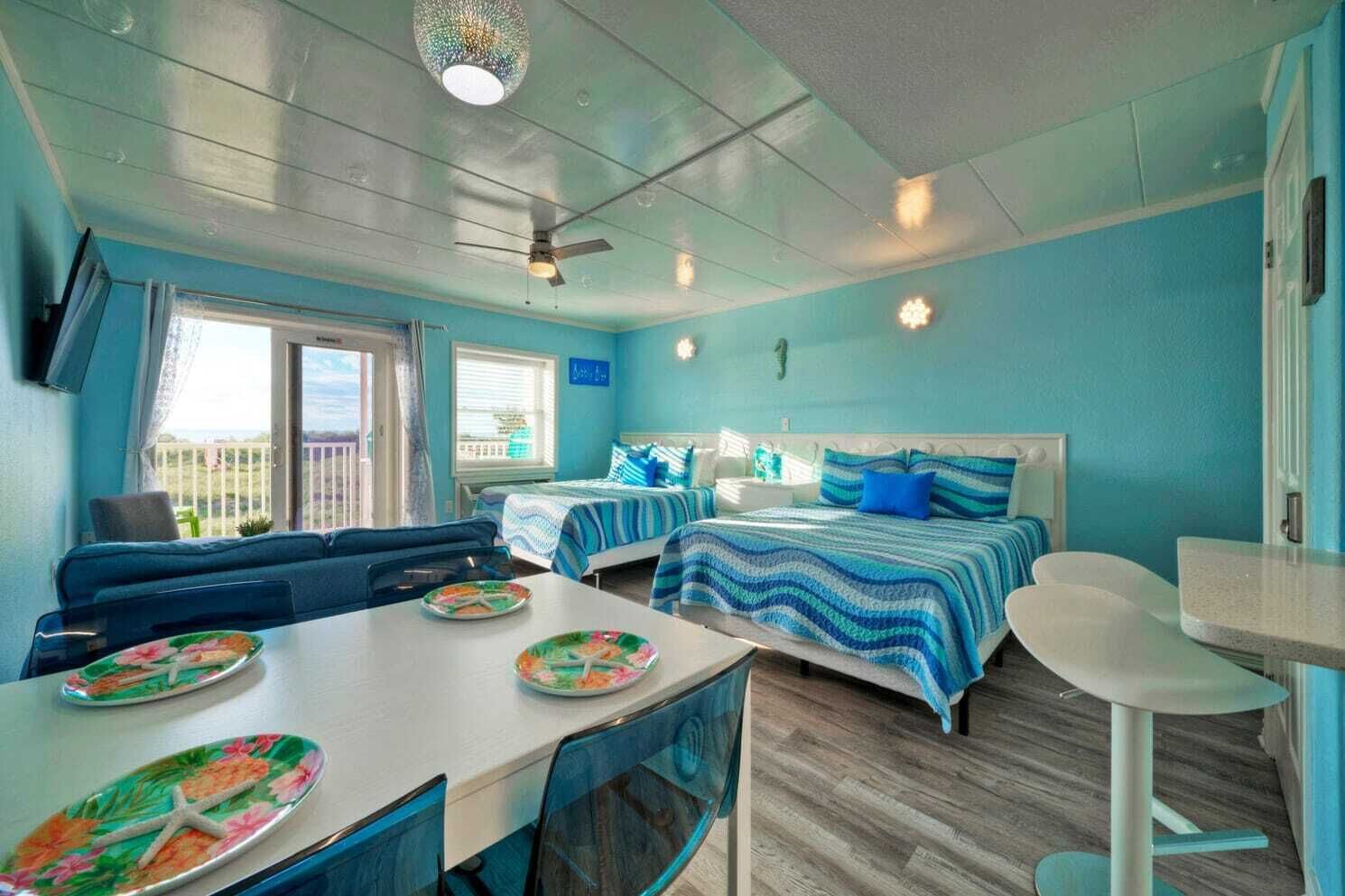 A room with two beds, a dining table with plates, and a ceiling fan.