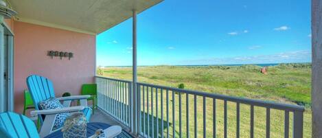 A balcony with a view of a grassy field and a clear sky.