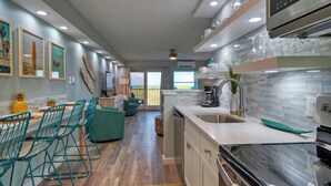 A modern kitchen with a dining area, a view to the outside, and a large island with a sink. - Beachfront Condo, Prvt Balcony w/ View, Pool Access Beach Happy by Avantstay (Port Aransas)