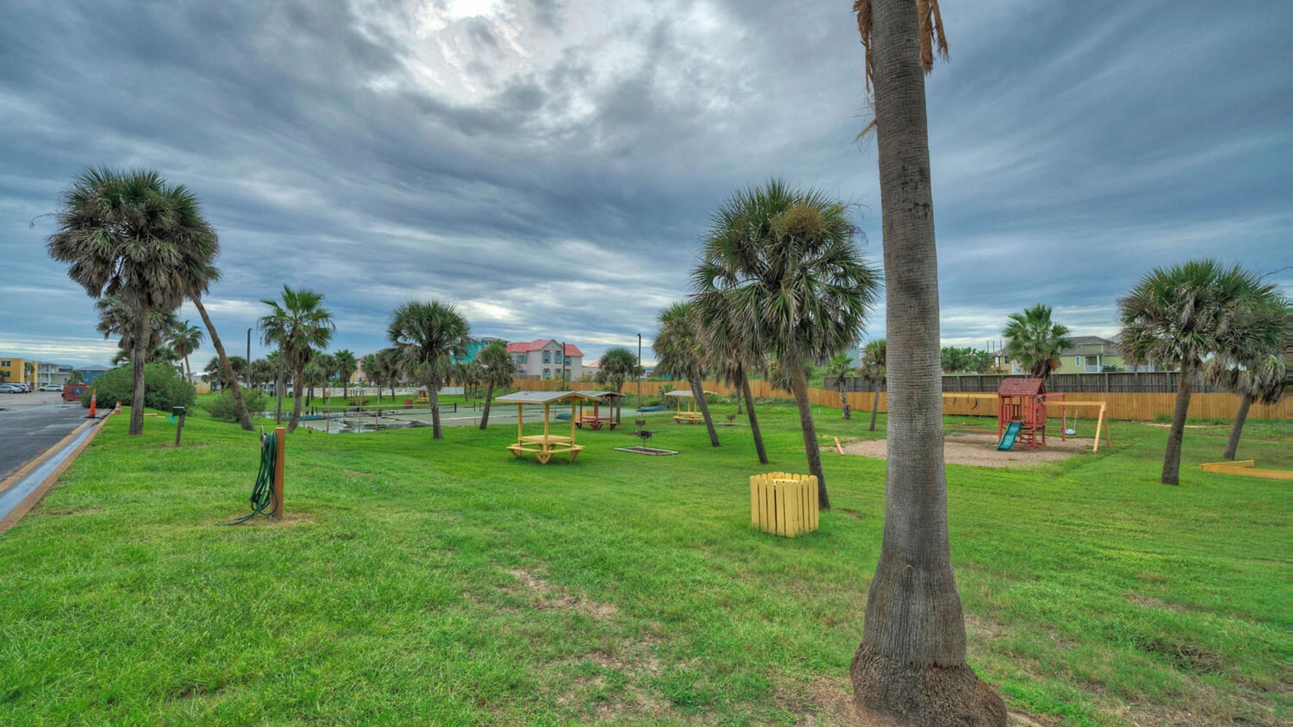 A park with palm trees, picnic tables, and a playground.