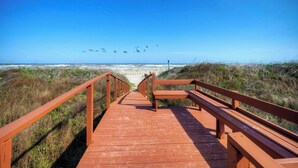 A wooden boardwalk leading to a beach with a clear sky. - Beachfront Retreat w/ 2 Pools + Tennis + Bikes + Boardwalk Pura Vida by Avantstay (Port Aransas)