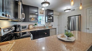 A modern kitchen with granite countertops, stainless steel appliances, and pendant lighting. - Beachfront Retreat w/ 2 Pools + Tennis + Bikes + Boardwalk Pura Vida by Avantstay (Port Aransas)