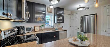 A modern kitchen with granite countertops, stainless steel appliances, and pendant lighting.