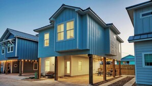 A row of blue houses with a covered patio area and a wooden fence.