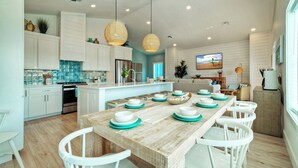 A modern kitchen with white cabinets, a wooden island with teal plates, and pendant lights.
