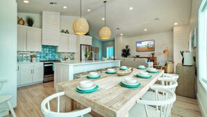 A modern kitchen with white cabinets, a wooden island, and teal accents.