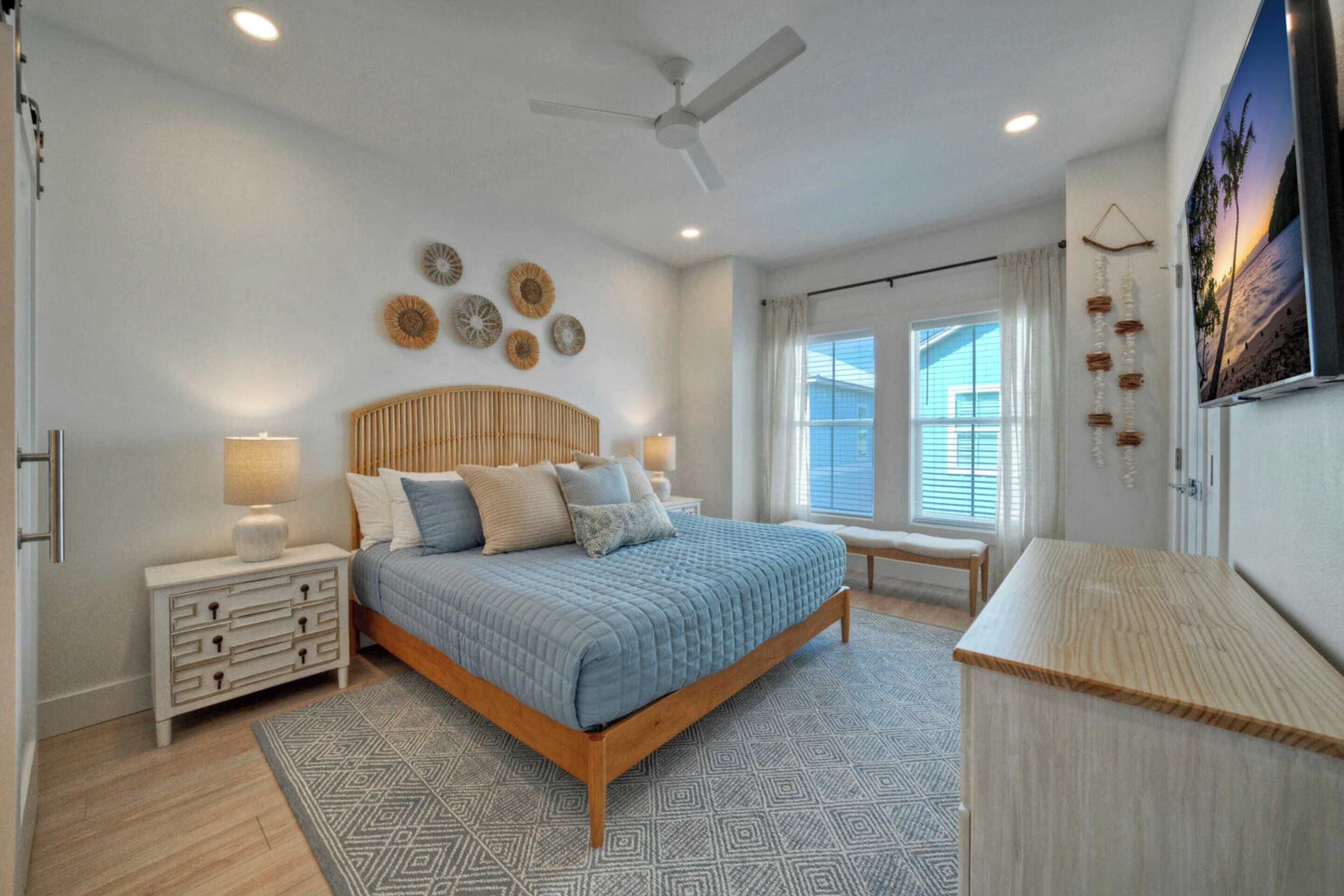 A bedroom with a bed, bedside tables, a ceiling fan, and a window with curtains.