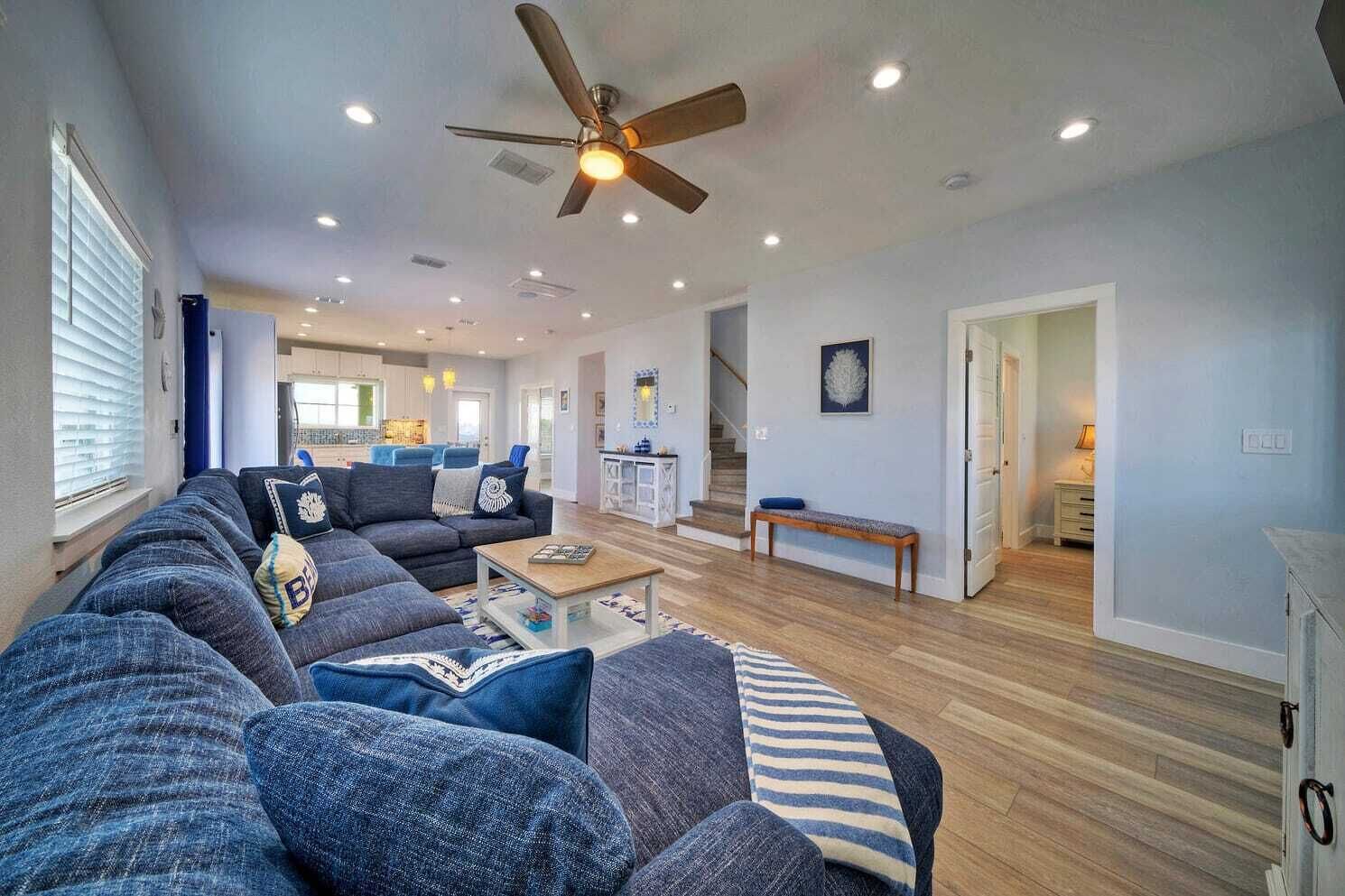 Ein geräumiges Wohnzimmer mit einer großen Eckcouch, einem Couchtisch und einem Deckenventilator.