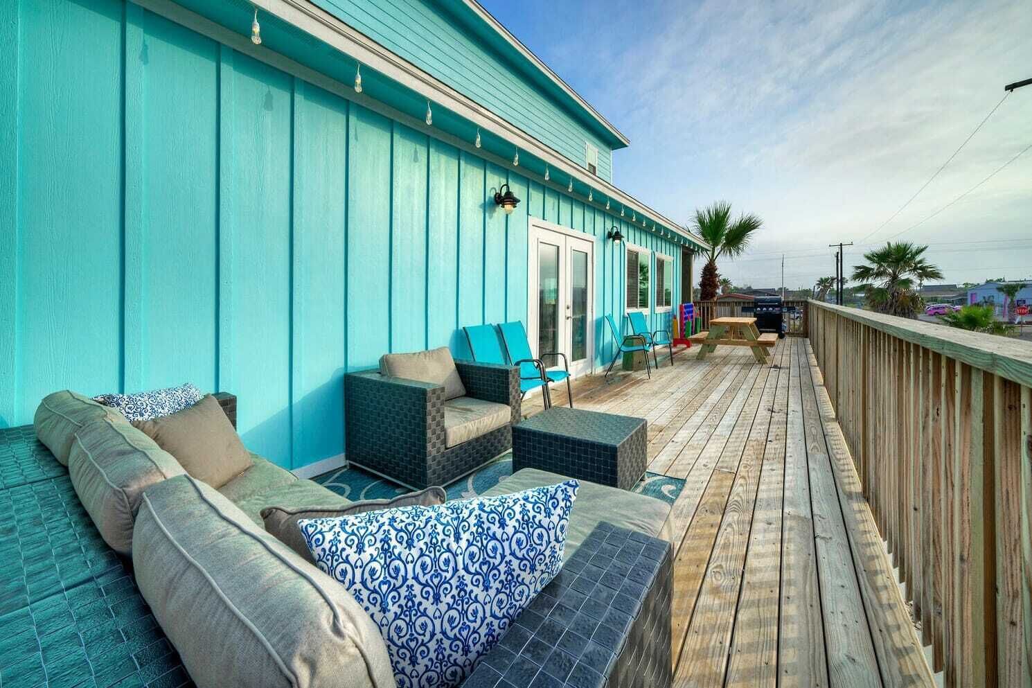 A wooden deck with outdoor seating, including sofas and chairs, and a wooden railing.