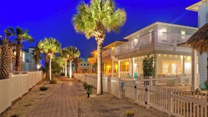 A beachfront hotel with a paved walkway, palm trees, and a white fence. - Gated Community w/ Pool 5mins to Beach Latitude Adjustment by Avantstay (Port Aransas)
