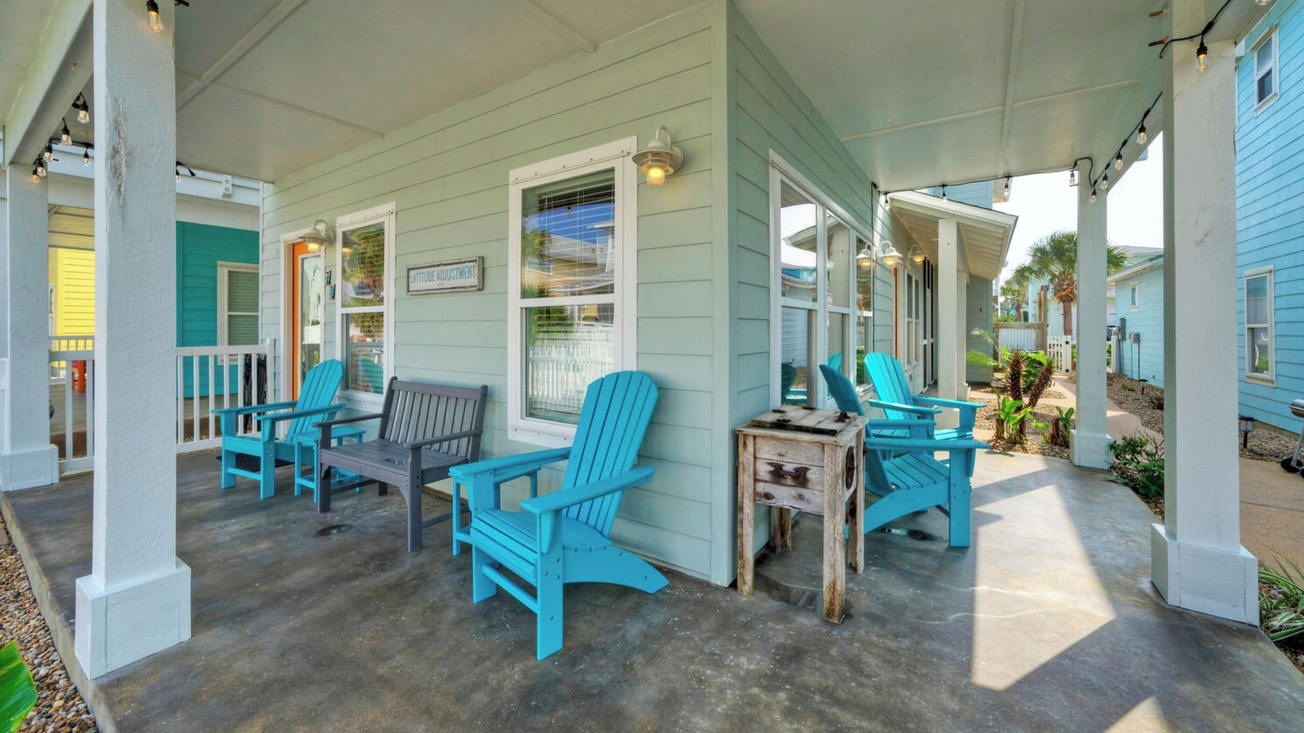 Eine überdachte Veranda mit Adirondack-Stühlen, einer Holzbank und einem kleinen Tisch.