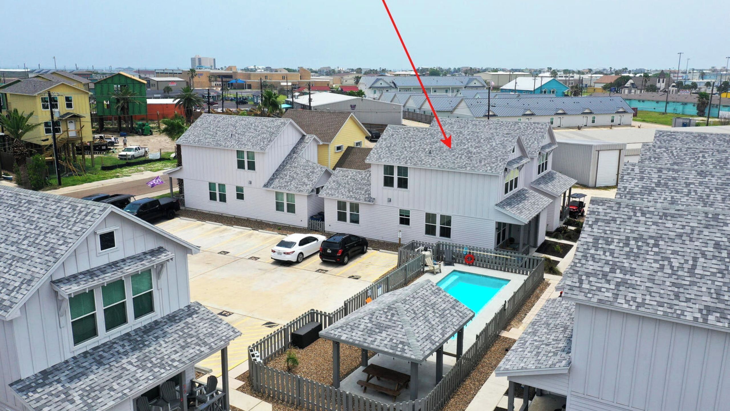 A residential area with houses, a swimming pool, and a fenced patio area.