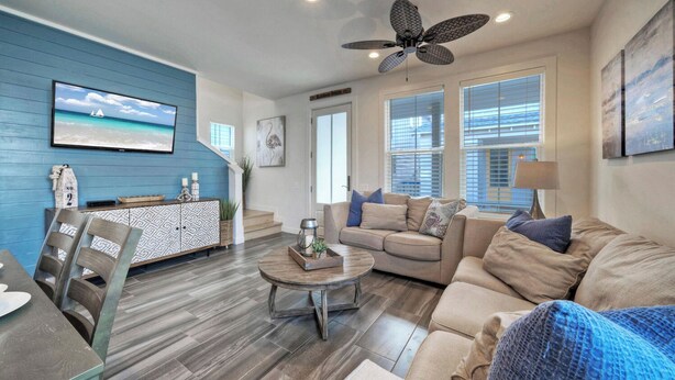 A living room with a blue accent wall, a ceiling fan, a sofa, a coffee table, and a TV. - Pool 1 Block to Alister + Old Town + Eateries Bluegrass Breeze by Avantstay (Port Aransas)