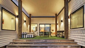 A covered outdoor area with a wooden staircase leading up to a seating area with a table and chairs. - Modern Design, 3 Mins to the Beach Boat Parking The Beach Box by Avantstay (Port Aransas)
