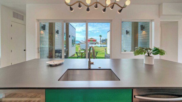 A modern kitchen with a large island, stainless steel sink, and a unique chandelier. - Modern Design, 3 Mins to the Beach Boat Parking The Beach Box by Avantstay (Port Aransas)