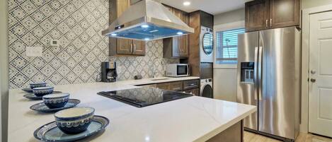 A modern kitchen with a central island, stainless steel appliances, and patterned backsplash.