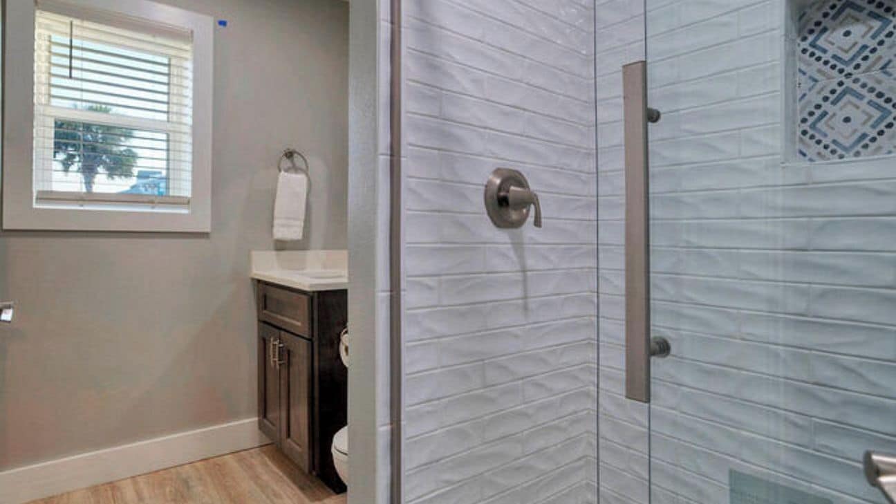 A bathroom with a shower, a toilet, a sink, and a window.