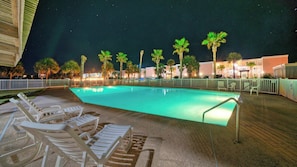 A swimming pool with lounge chairs, palm trees, and a building in the background. - Beachfront, Patio w/ Dune View, 2 Pools, Pickleball Cravin Waves by Avantstay (Port Aransas)