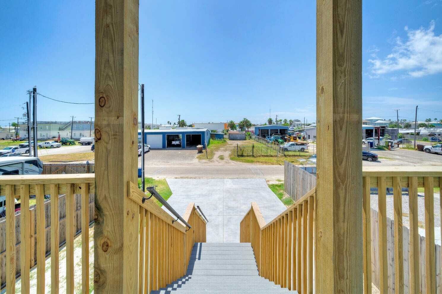 Una escalera de madera que conduce a un estacionamiento con vistas a un edificio comercial y vehículos.