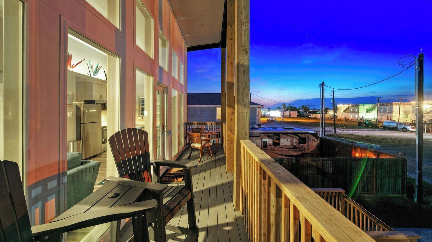 A balcony with a view of a town, a dining area with chairs and a table, and a kitchen area with appliances.