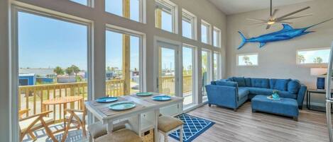A spacious living area with large windows, a ceiling fan, and a blue shark decoration.