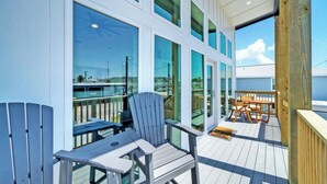 A deck with a chair, a table, and a view of the sea. - Dean Marlin by Avantstay Stunning Old Town Home! (Port Aransas)