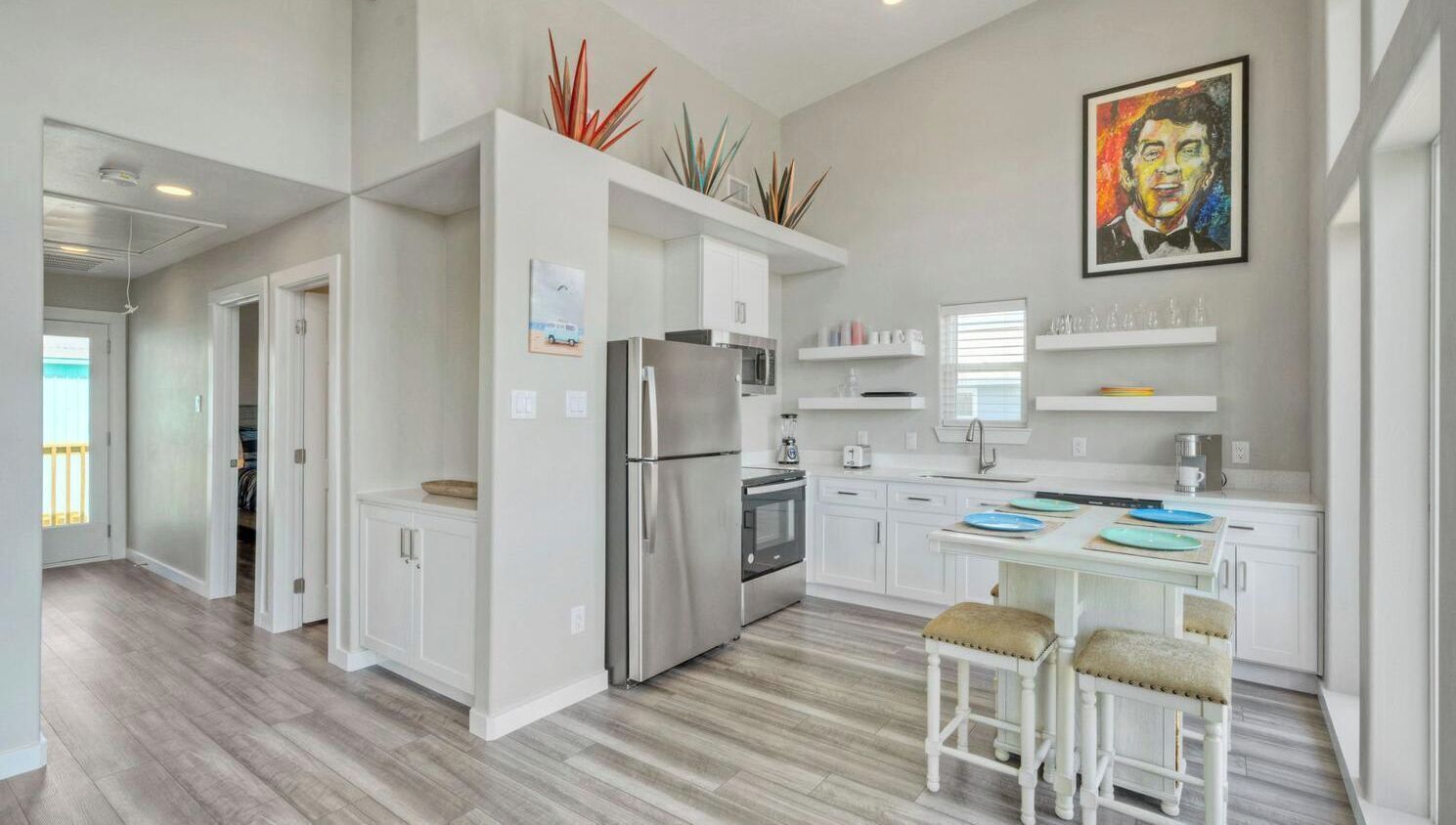 A modern kitchen with white cabinetry, stainless steel appliances, and a dining area with a table and two chairs.