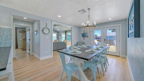 A dining area with a long table, light blue chairs, and a chandelier.