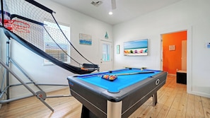 A pool table with balls, a pool cue, and a netted area for diving. - 2 Blocks to the Beach, Pool, Patio w/ Bar Awave From it All by Avantstay (Port Aransas)