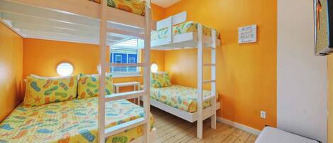 A room with bunk beds, a window, and a sign on the wall.