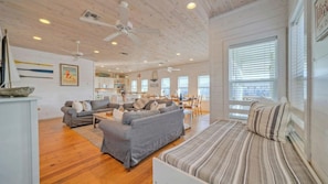 A spacious living area with a sofa set, a dining table, and a kitchen in the background. - Best Little Shore House by Avantstay Fishing Pond Views + Fire Pit + Hammock Lounge + Pool (Port Aransas)
