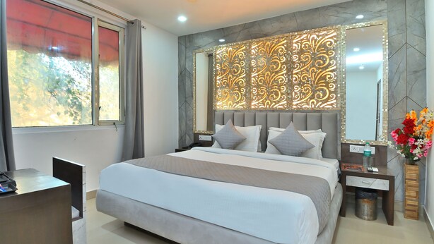A modern bedroom with a large bed, a desk, and a vanity with a mirror. - Hotel Bella Vista New Delhi-walk from New delhi railway station (New Delhi)