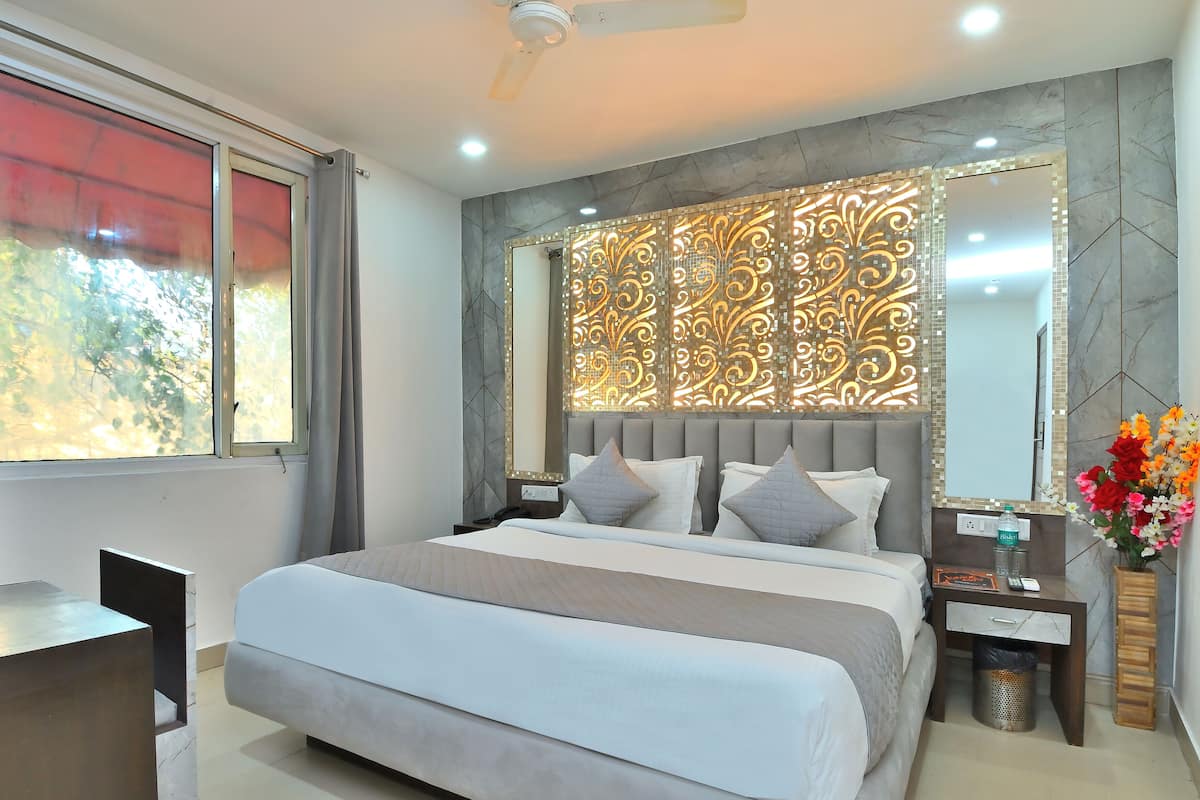 A modern bedroom with a large bed, a desk, and a vanity with a mirror.