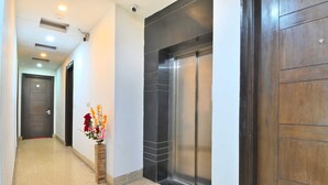 A hallway with a wooden door, a black-tiled wall, and a flower vase. - Hotel Bella Vista New Delhi-walk from New delhi railway station (New Delhi)