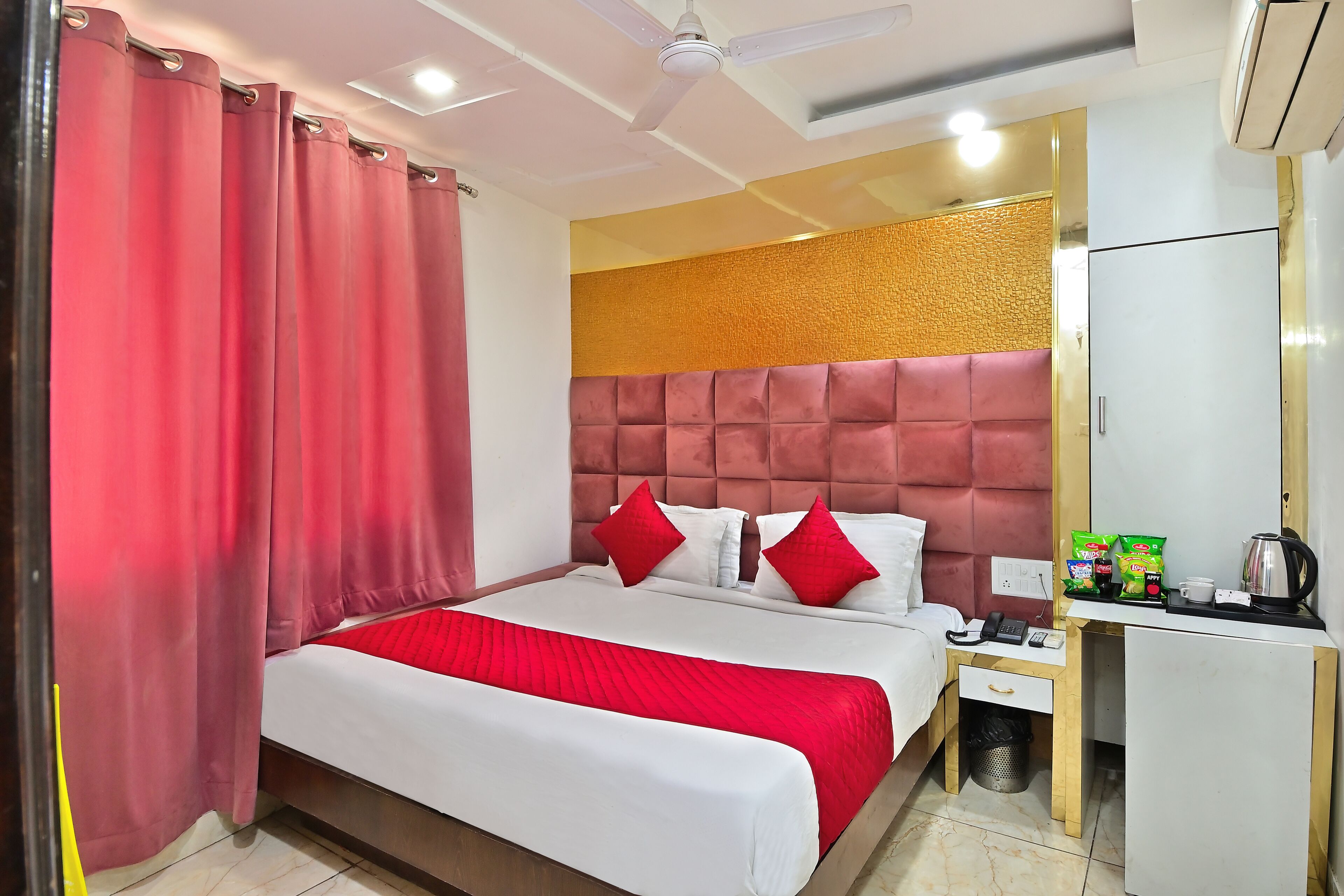 Une chambre d’hôtel équipée d’un lit, d’un bureau, d’une chaise, d’une poubelle et d’un ventilateur de plafond.