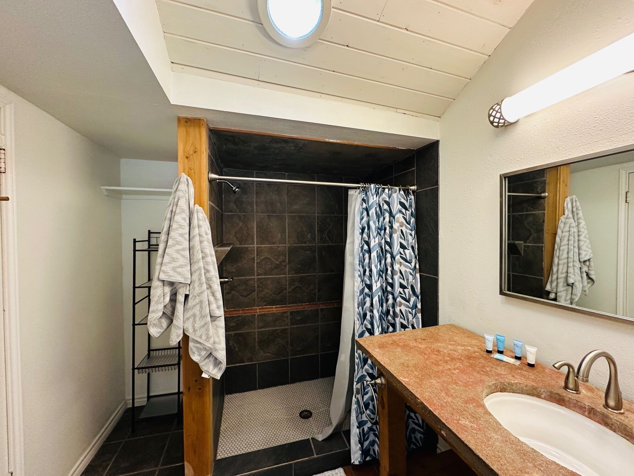 A bathroom with a shower, a sink, and a mirror.