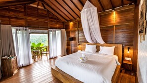 A wooden cabin-style bedroom with a large bed, a canopy, and a view of greenery outside. - Bali De Pardis Cottage (Munduk)