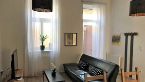 A modern living room with a black leather sofa, a wooden coffee table, a TV on a stand, and a potted plant. - Cozy 2 bedroom Apart with balcony in Ottakring (Vienna)