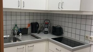 Een compacte keuken met witte kastjes, een zwart aanrecht en een ingebouwde kookplaat.