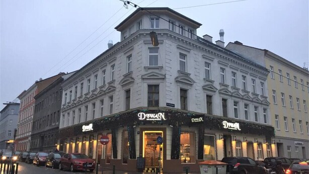 Un bâtiment avec une entrée située à l’angle, orné d’une enseigne indiquant « Dresde » et d’une autre enseigne indiquant également « Dresde ».
