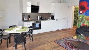 Une cuisine moderne avec des meubles blancs, un four noir et un coin repas comprenant une table ronde et des chaises noires.