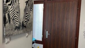 Une pièce avec une porte en bois, un radiateur et un tableau représentant un zèbre accroché au mur.