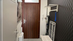 Un couloir étroit avec une porte en bois, un radiateur et un porte-serviettes.