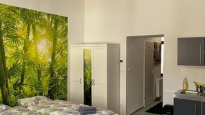 Une chambre à coucher comprenant un lit, une armoire, un bureau avec une chaise, et une salle de bain visible à travers une porte ouverte.