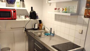 A compact kitchen with a microwave, stove, and sink. - Studio Apartment near Reumanplatz (Vienna)