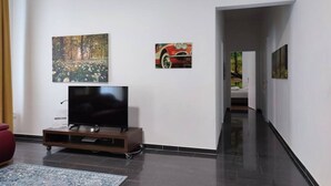 Un salon moderne avec un téléviseur à écran plat posé sur un meuble en bois, un canapé rouge et deux tableaux accrochés aux murs.